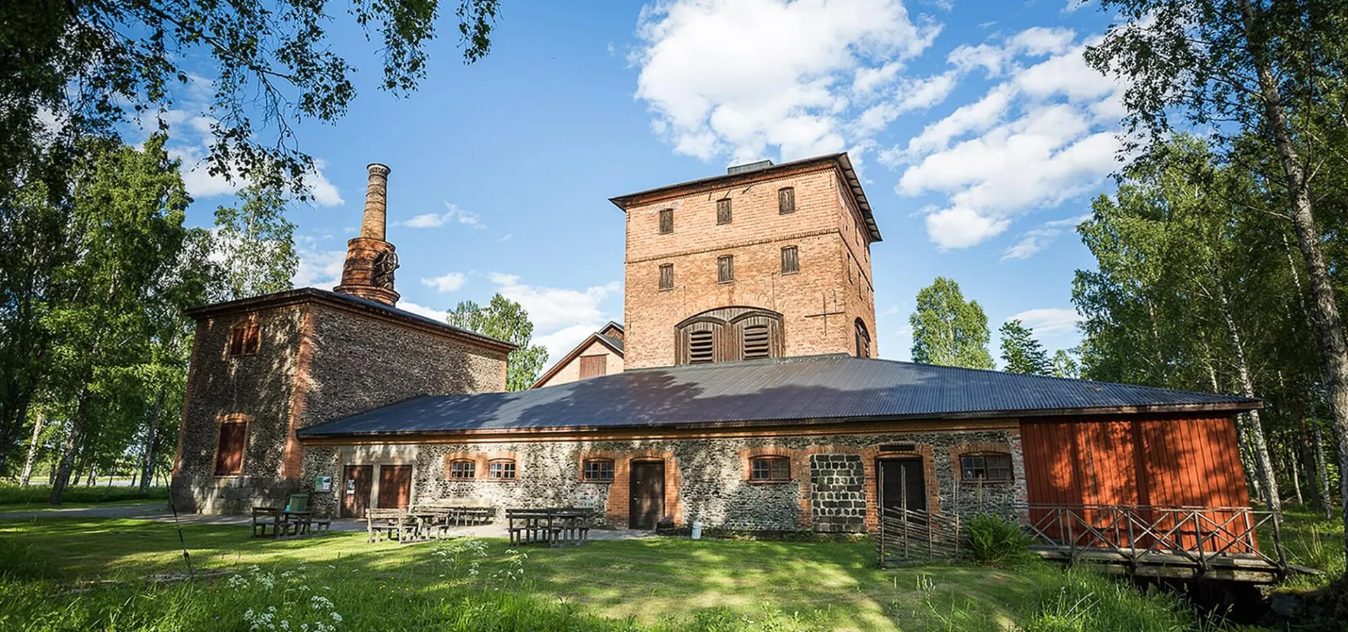 Det gamla bruket Hyttan av tegel inbäddat i grönska en vacker sommardag