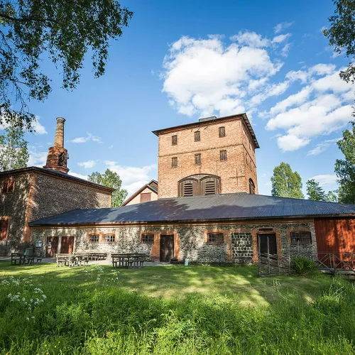 Det gamla bruket Hyttan av tegel inbäddat i grönska en vacker sommardag